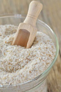 Weiße Flohsamenschalen im Glas mit Holzschäufelchen