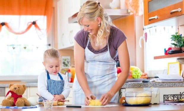 Mutter und Kind mit Schürze backen Plätzchen