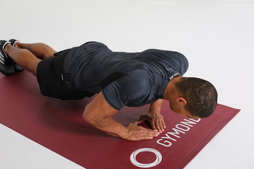 Mann macht Diamond Push Ups auf dunkelroter Trainingsmatte