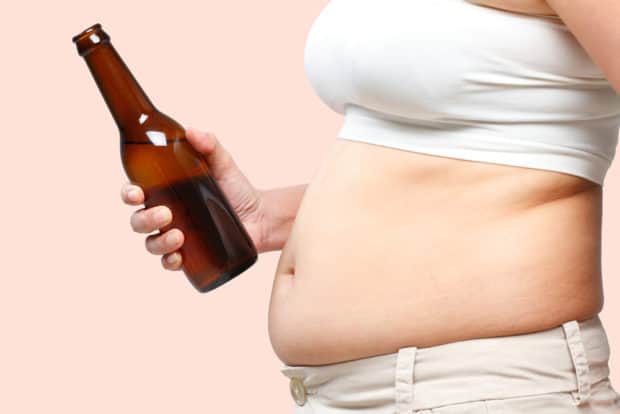 Dicker Bauch einer Frau, die eine Bierflasche in der Hand hält