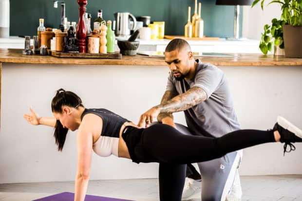 Dominic Harrison zeigt an einer jungen Frau die Ausführung von Bodyweight Übungen im GET STRONG Programm