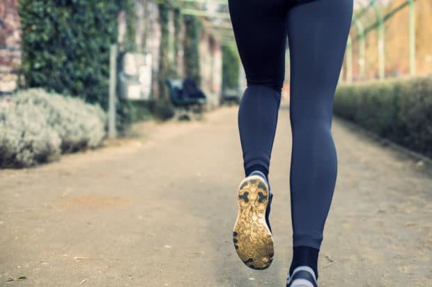 Beine einer jungen Frau in Sportleggins die joggt