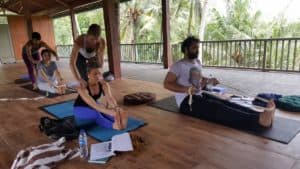 Yogaklasse auf Bali, Yogalehrerin korrigiert eine junge Frau in der Vorbeuge