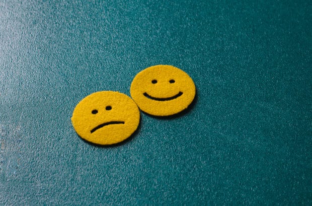 Zwei gelbe Smileys vor blauem Hintergrund. Einer lacht einer ist traurig.