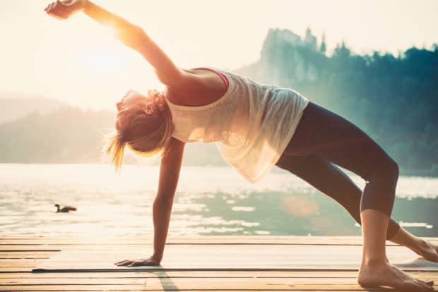 Junge Frau macht Yoga am See und fühlt sich wohl