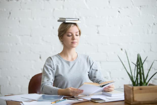 Frau sitzt gerade mit einem Buch auf dem Kopf bei der Arbeit