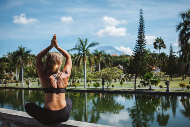 Junge Frau sitzt im Lotussitz und macht Yoga auf bali