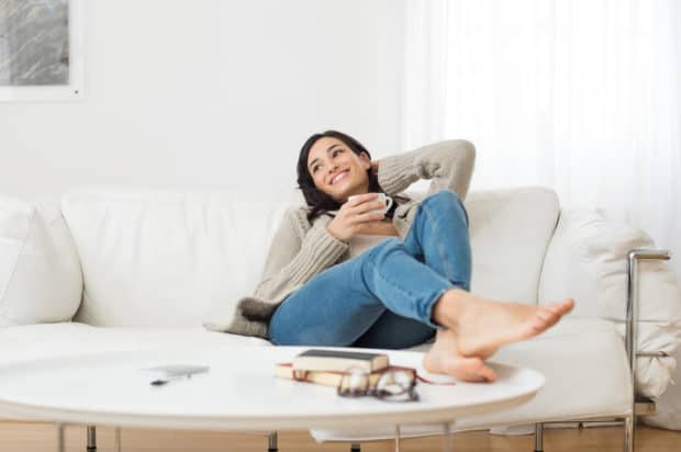 Frau sitzt entspannt auf dem Sofa mit Tasse Tee