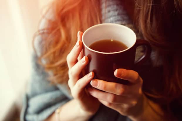 Frau hält Tasse mit heißem Tee in den Händen