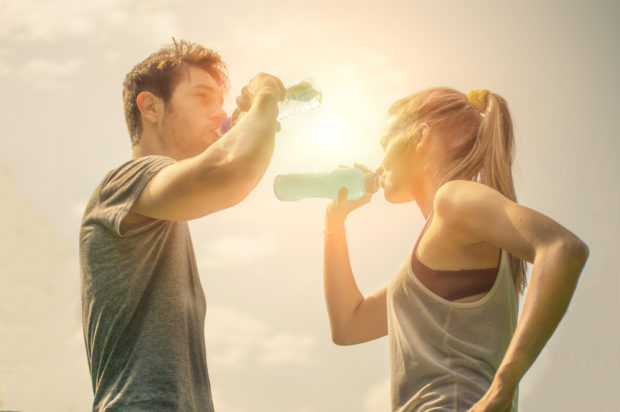 Frau und Mann stehen sich gegenüber und trinken Wasser