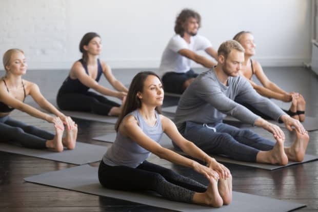 Gruppe von Männern und Frauen machen Yoga für Sportler - die Vorbeuge